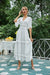 Mujer joven en un jardín con un vestido blanco ibicenco