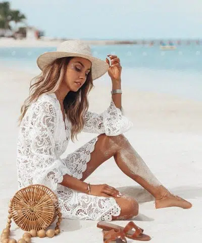 Mujer hippie sentada sobre la arena con un vestido de encaje Adlib