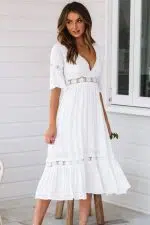 Joven mujer morena con sandalias y vestido blanco largo