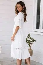 Mujer de pie y de espaldas con vestido blanco en Ibiza