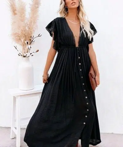 Mujer rubia con un vestido ibicenco negro y un clutch de cuero para la noche